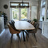 Moderne Eettafel Deens Ovaal Fjord van Design85 met ovaal eikenhouten tafelblad en zwart stalen frame in een sfeervolle eetkamer.