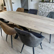 Eettafel Deens Ovaal Fjord met natuurlijke houtnerf en industrieel onderstel, omringd door comfortabele antracietkleurige eetkamerstoelen.