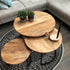 ronde salontafel mango met 2 plantjes en een kaars op een zwart kleed met een bank op de achtergrond 