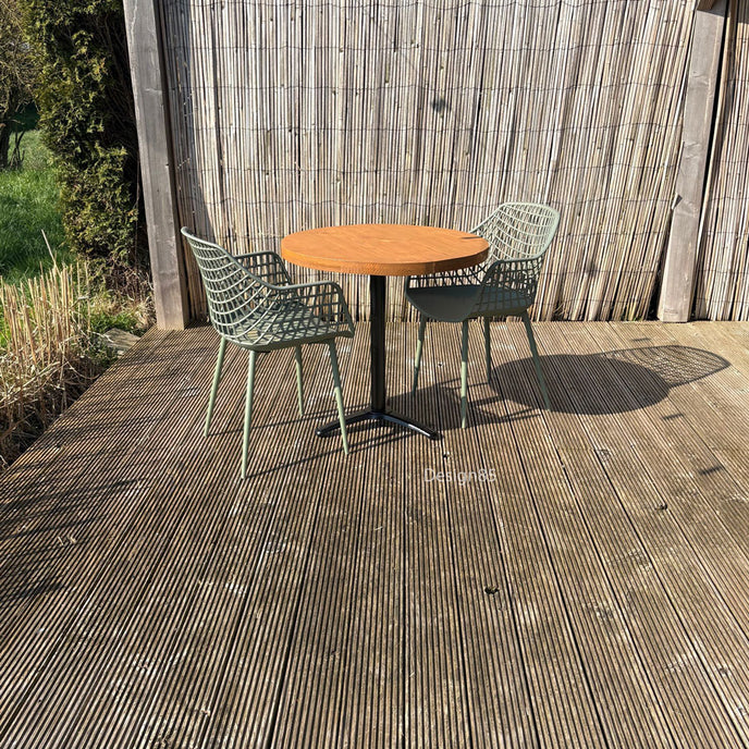 Terrasmeubelset met compacte ronde tafel, zwart onderstel en twee groene stoelen op een houten vlonder in de tuin.