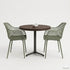 Ronde horecatafel met een tafelblad in Rich Brown kleur, gecombineerd met twee groene designstoelen met open rasterstructuur en een zwart metalen onderstel in een minimalistische studio-opstelling.