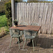 Industriële terras tafel met houten blad en zwart onderstel in zonnige tuinsetting