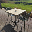 Houten bartafel met zwart metalen onderstel in een sfeervolle achtertuin met gezellige zithoek.