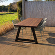 Houten tuintafel met A-frame onderstel en groene stoelen op terras in de achtertuin