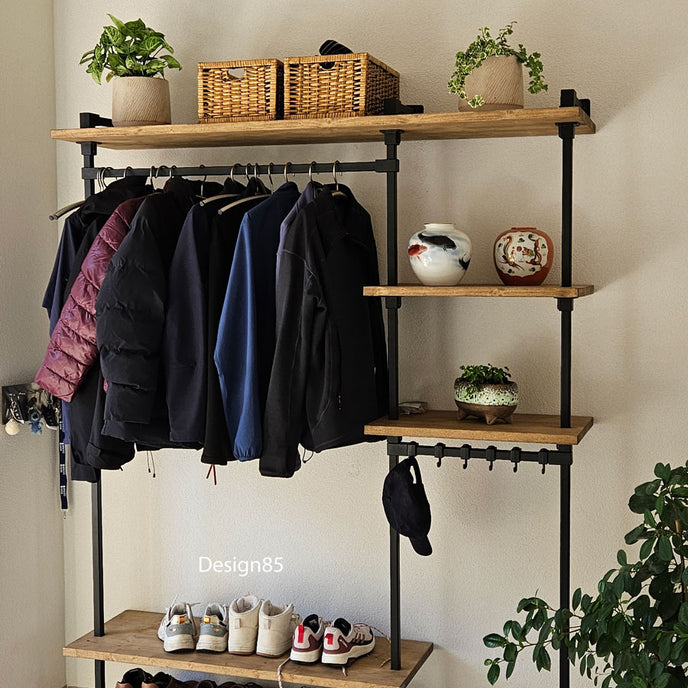 kapstok van zwart metaal met houten planken, kledingroede en schoenenrek in een moderne hal.