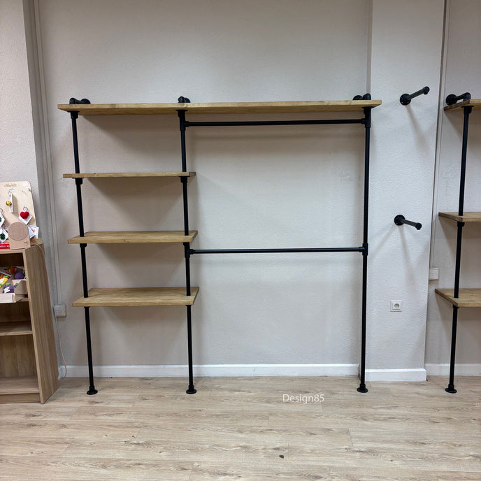 Kinder kledingrek aan de muur met open vakken, zwarte buizen en houten planken voor kleding en opbergruimte.