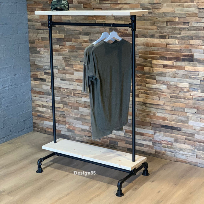 Kledingrek wielen planken in industriële stijl met witte houten legplanken, zwarte buizen en hangende kleding.