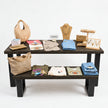 Presentatietafel winkel met zwart gebeitste houten bladen en industrieel stalen onderstel voor het presenteren van kleding en accessoires.