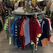 Rond steigerbuis kledingrek met kleding en sneakers in een moderne vintage kledingwinkel.
