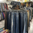 Industrieel rond kledingrek van steigerbuizen gevuld met kleurrijke polo’s en shirts in een kledingzaak.