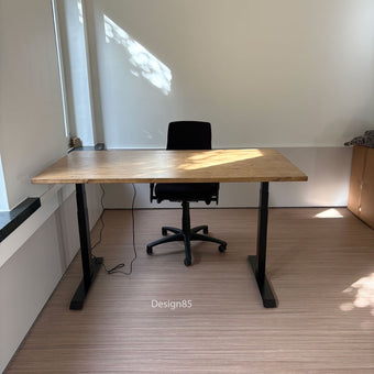 Zit sta bureau hout met natuurlijk houten bureaublad en zwart verstelbaar onderstel in een lichte kantoorruimte.